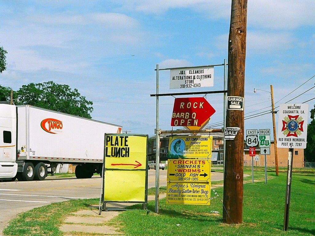 A row of hand-painted local-business signs on a small-town main street in Coushatta, Louisiana · J&L Cleaners, Rock BBQ, Plate Lunch, Crickets / Shiners / Worms, Agnes' Beauty Salon · the exact kind of business local SEO is supposed to find.